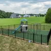 Playground with black fence and green rubber mulch