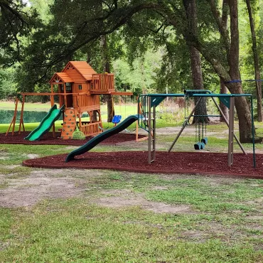 2 playgrounds with red rubber mulch ground cover
