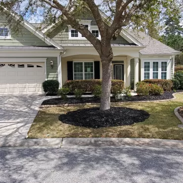 A front yard with black rubber mulch in the garden beds