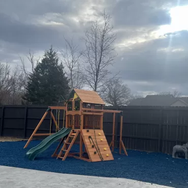 Backyard playground with blue rubber mulch base