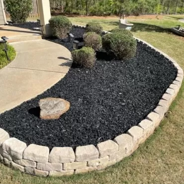 Black rubber mulch garden bed with stone trim