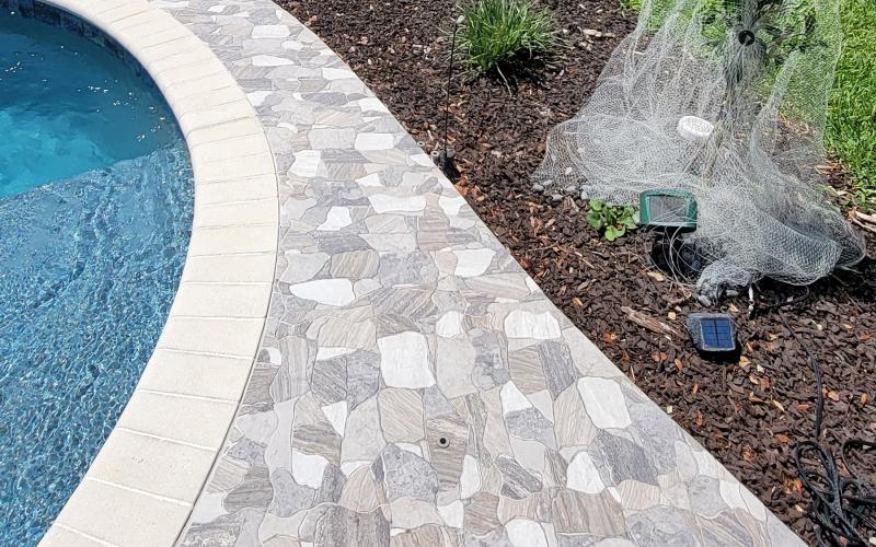 Pool pavers with brown rubber mulch along the edge