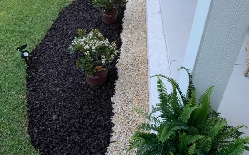 Brown rubber mulch landscape bed in front of home entrance.
