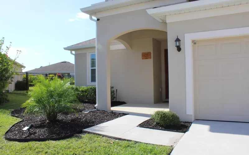 House with brown rubber mulch beds near entryway