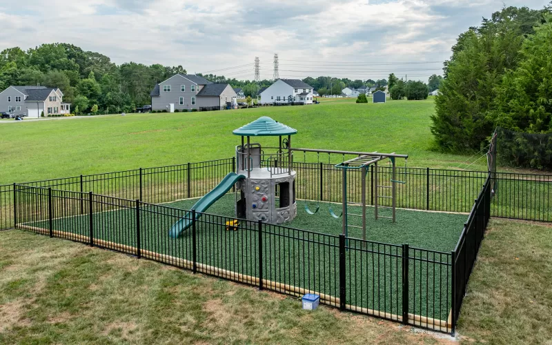 Playground with black fence and green rubber mulch
