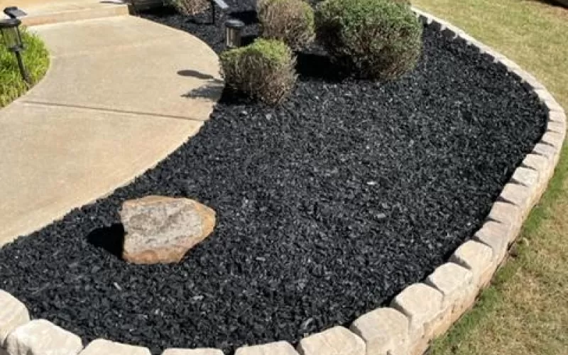Black rubber mulch garden bed with stone trim