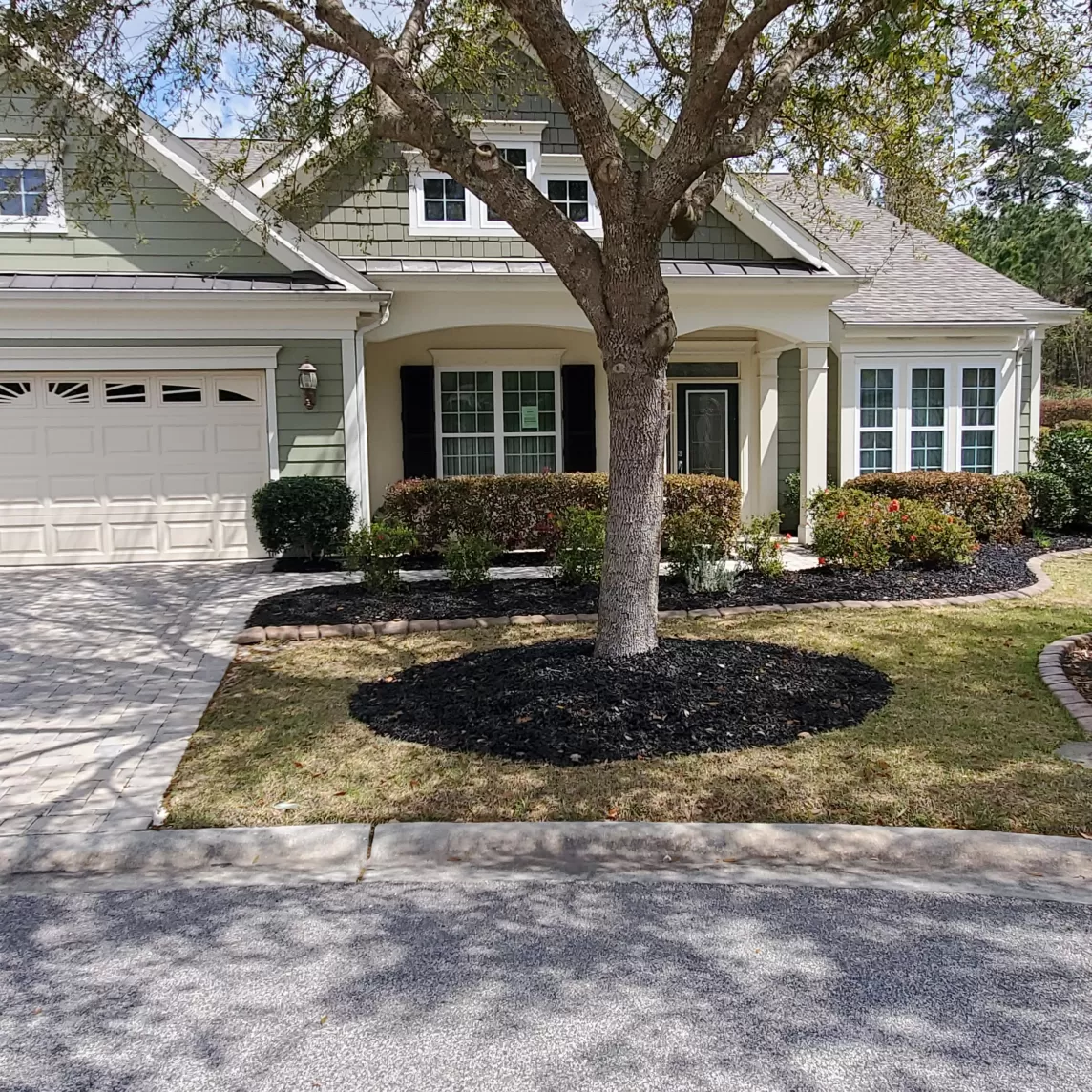 A front yard with black rubber mulch in the garden beds