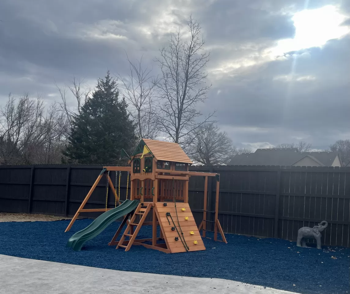 Backyard playground with blue rubber mulch base