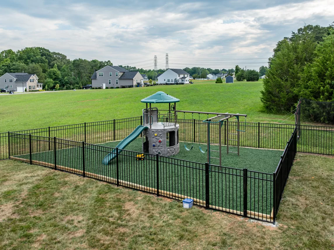 Playground with black fence and green rubber mulch