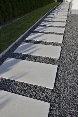 A landscaped yard path with large square paver stones surrounded by custom grey rubber mulch.